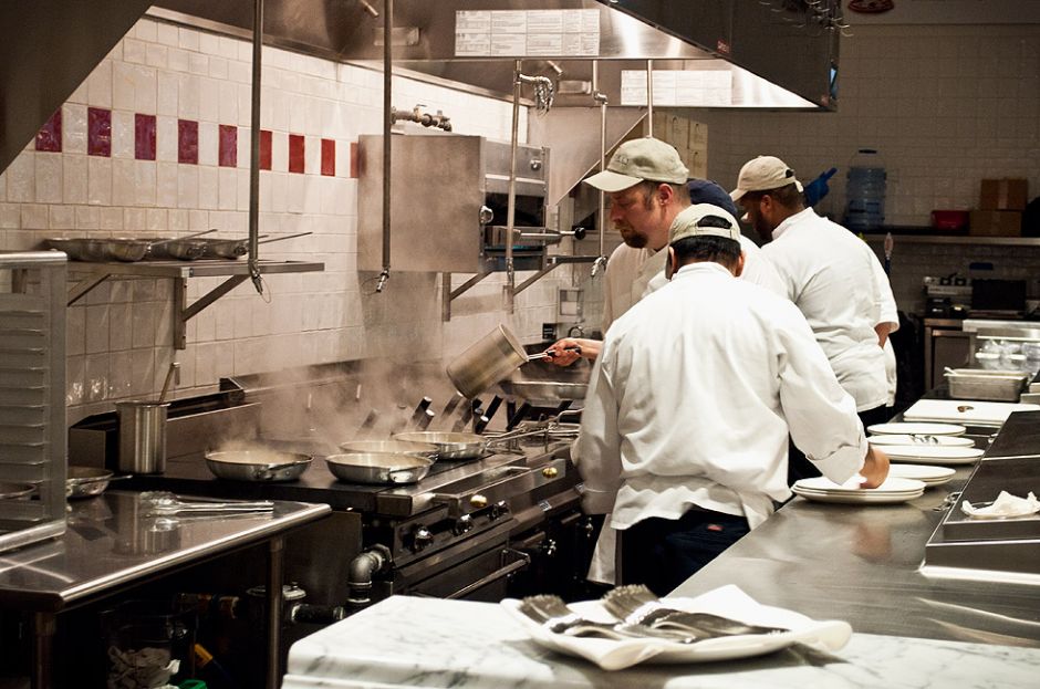 A full kitchen brigade in white jackets working a busy service line